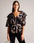 JASMYNA-Tops-Ruffled to perfection and finished with a bow, JASMYNA is your ticket to style heaven. Bottomless brunch? More like your own personal catwalk.The fabric of this product is made of 100% recycled polyester. Using recycled polyester helps divert plastic waste from ending in landfills and helps us to reduce our dependancy on virgin materials. Ruffled top V-neck Abstract print Short sleeved Low back with tie fastening and zip Amy is 5'9.5" / 1.77m and wears Black in a Ted size 1- Ted Baker Romania
